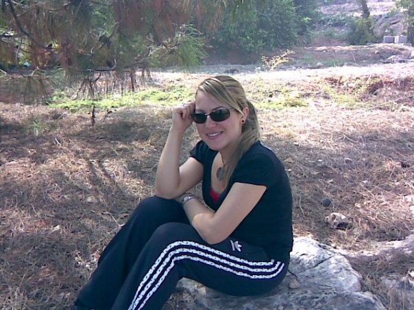 Adidas womans black pants with white stripes sitting sunglasses