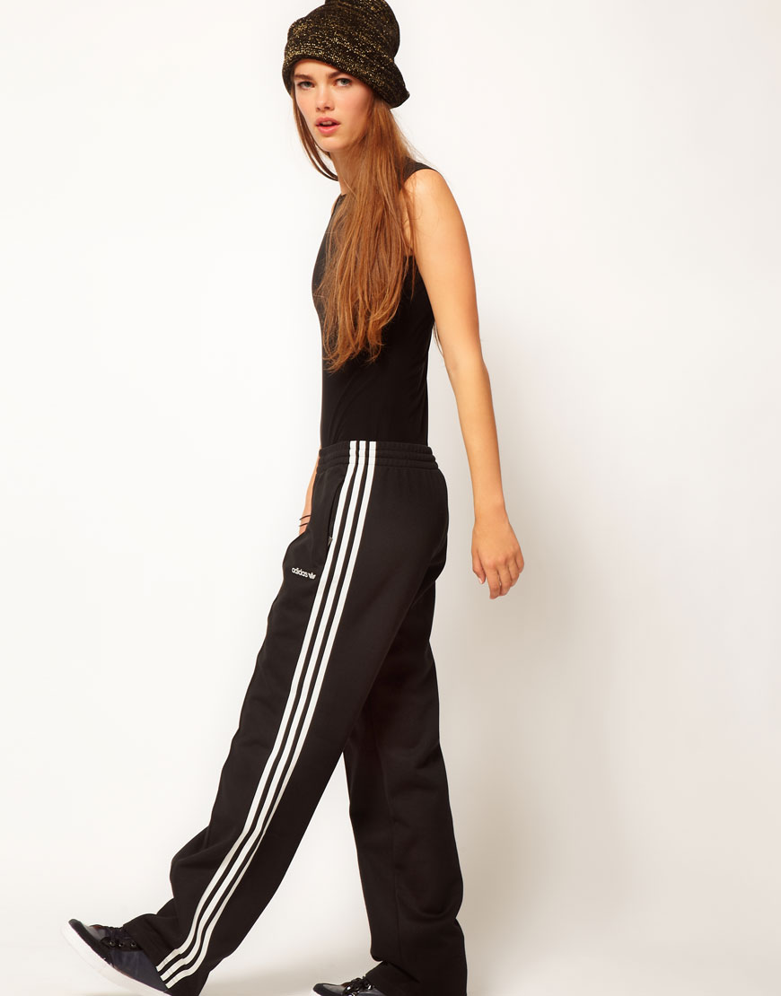 Adidas womens black pants with white stripes long legs pose